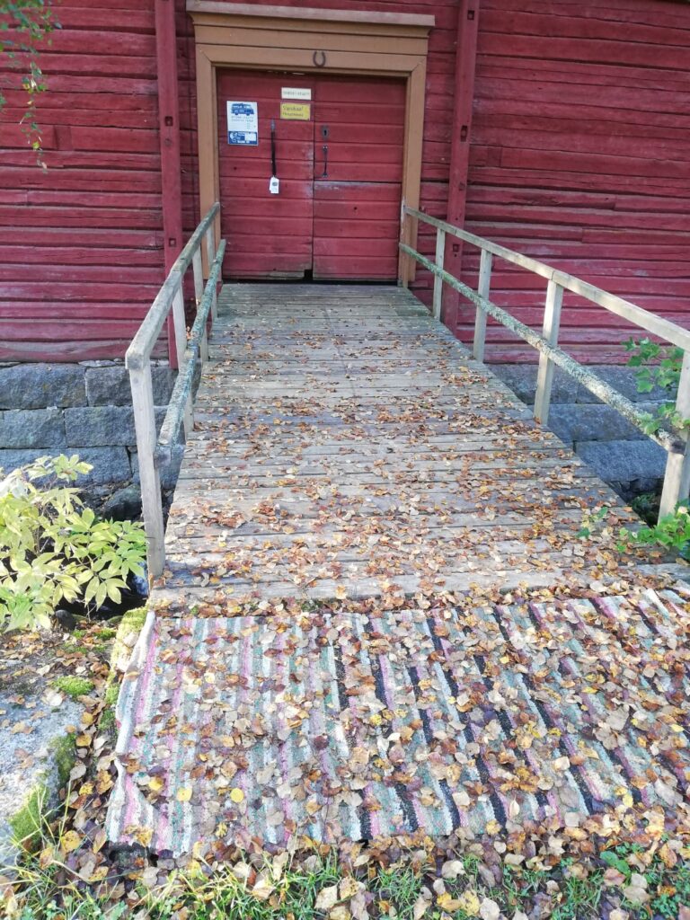 Myllyn ovi kiinni ja sinne vievällä sillalla pudonneita lehtiä.
